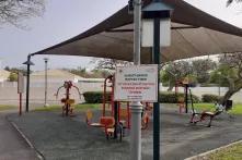 Ein Pavillon mit Fitnessgeräten in einem Park, davor ein Schild mit hebräischer Aufschrift
