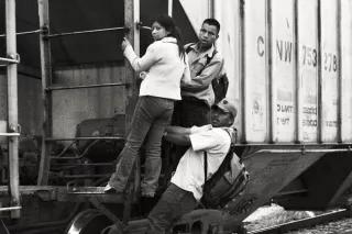 Drei Menschen halten sich an einem Eisenbahnwaggon fest