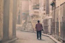 Man walks down a narrow empty street in Cairo, Egypt. 
