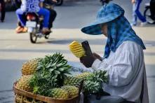 Ein Mensch schneidet Ananas an einer Straße
