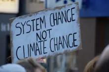 "System change not climate change" is written on a sign.