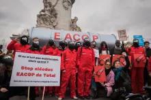 Eine Delegation ugandischer Aktivisten schließt sich dem STOP EACOP-Block beim Look UP-Klimamarsch in Paris, Frankreich, an, um das klimaschädliche Projekt von Total, die East Africa Crude Oil Pipeline, anzuprangern. Aktivisten in roten Squid-Game-Kostümen mit Total-Energies-Logo auf Masken halten eine gefälschte Pipeline, um Total aufzufordern, sich von fossilen Brennstoffen zu trennen.