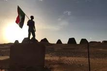 Mensch steht mit Sudanflagge beim Sonnenuntergang