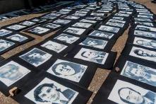 Auf dem Boden ausgelegte und dicht aneinandergereihte Porträts in Schwarzweißfotografie von Verschwundenen