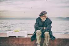 Europa? War da was? - Ein alter Mann sitzt auf einer Mauer am Meer