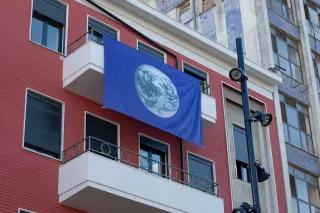 Büro der Heinrich-Böll-Stiftung in Tirana - rotes, mehrstöckiges Gebäude mit am Balkon hängenden blauen Fahne mit Erdkugel